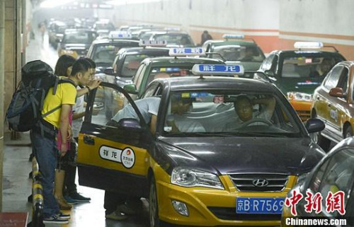 市民在北京西客站出租車候車點(diǎn)準(zhǔn)備乘車。中新社發(fā) 侯宇 攝