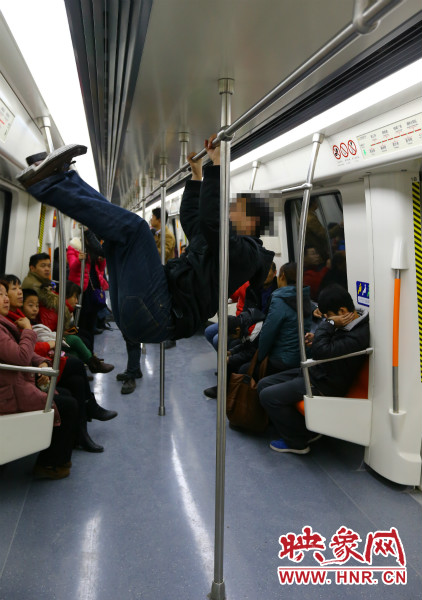 地鐵試乘日，一男子在車(chē)廂內(nèi)攀爬扶手自?shī)首詷?lè)