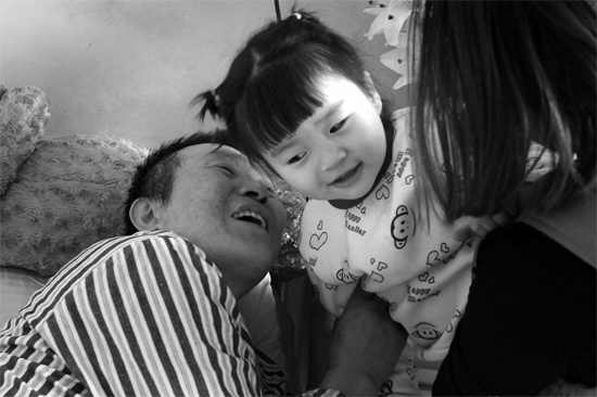 病床前李剛父女倆說著“悄悄話”，幸福的氣氛洋溢在病房中