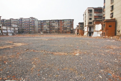 為降塵，旮旯王村拆遷后裸露的地面上鋪了一層石子。